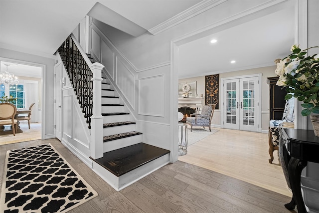 stairway with hardwood / wood-style flooring, an inviting chandelier, ornamental molding, and french doors