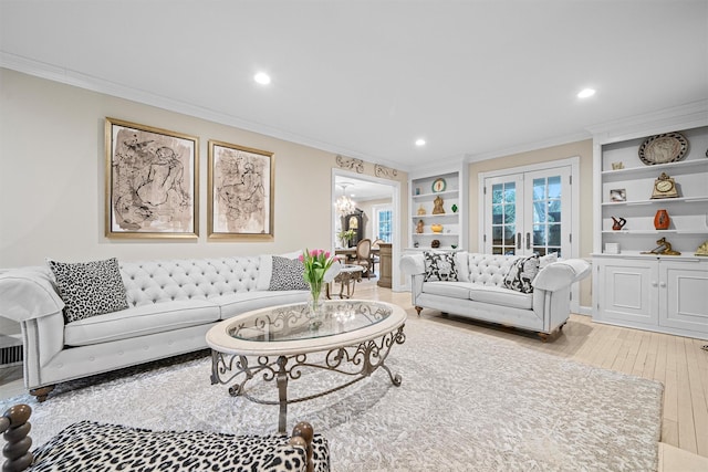 living room featuring built in shelves, french doors, crown molding, and light hardwood / wood-style flooring