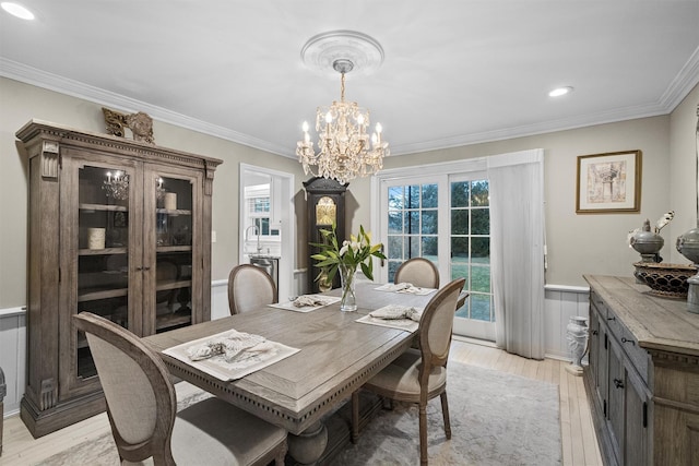 dining area featuring light hardwood / wood-style floors, ornamental molding, and a chandelier