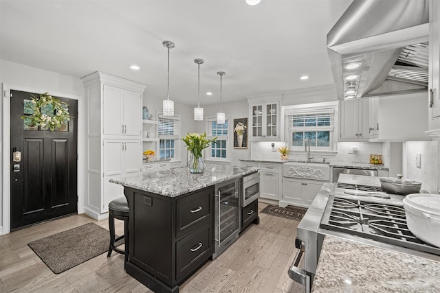 kitchen featuring range hood, a center island, appliances with stainless steel finishes, a breakfast bar area, and white cabinets