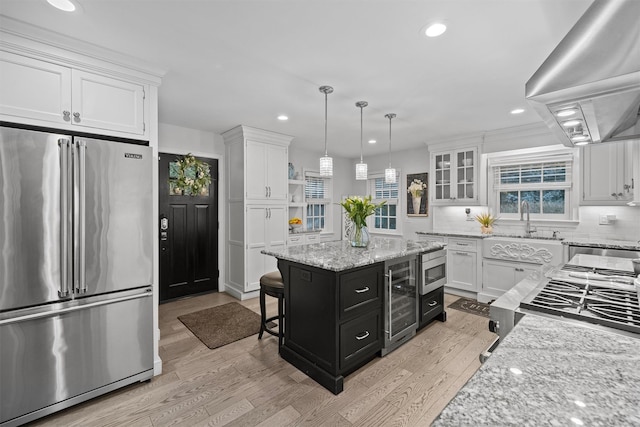 kitchen featuring island range hood, appliances with stainless steel finishes, pendant lighting, white cabinets, and a center island