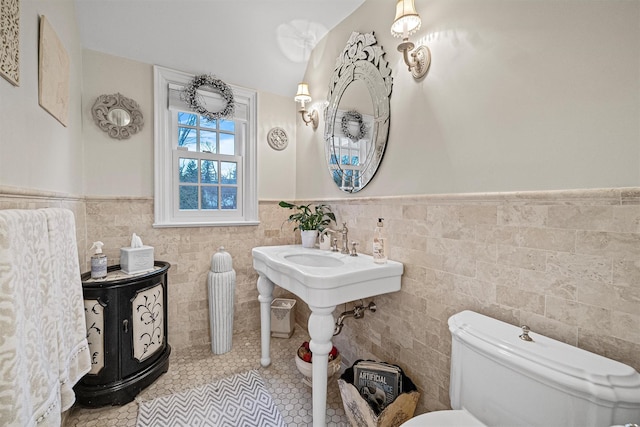 bathroom with toilet, tile walls, and tile patterned floors