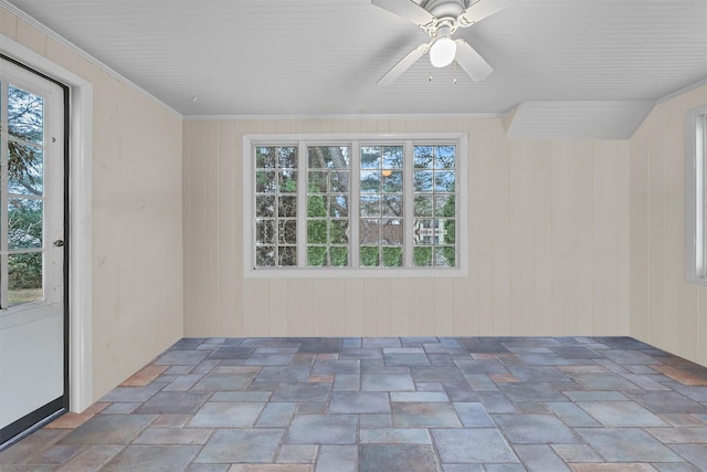 interior space with ceiling fan, crown molding, and wooden walls