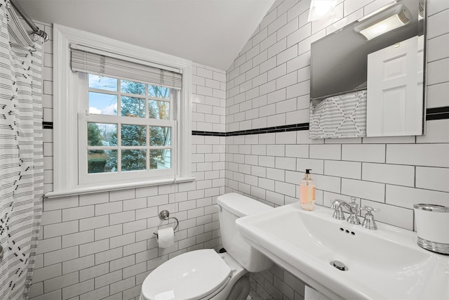 bathroom featuring tile walls, vaulted ceiling, and sink