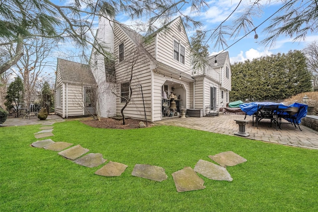 rear view of house featuring a patio area and a yard