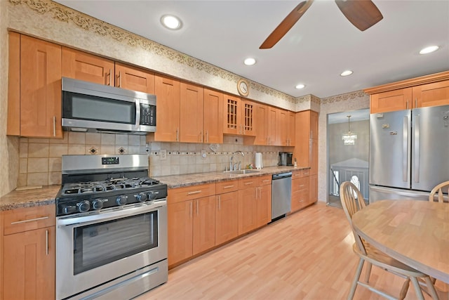 kitchen featuring light stone counters, stainless steel appliances, sink, and light wood-type flooring