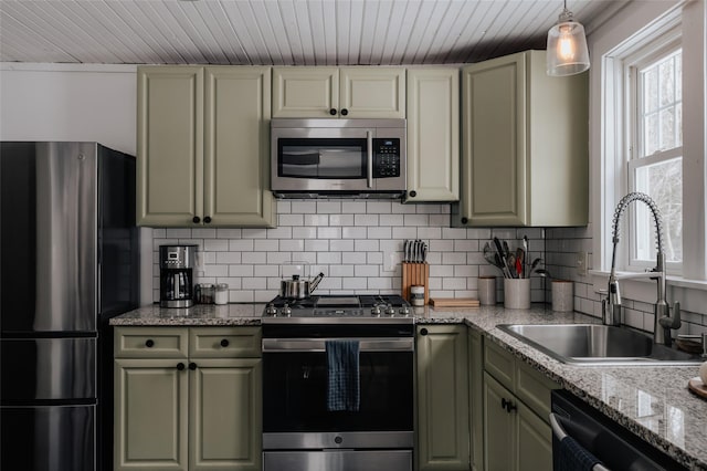 kitchen with appliances with stainless steel finishes, decorative backsplash, light stone countertops, pendant lighting, and sink