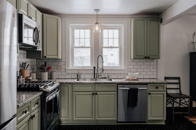 kitchen featuring appliances with stainless steel finishes, pendant lighting, light stone counters, and sink