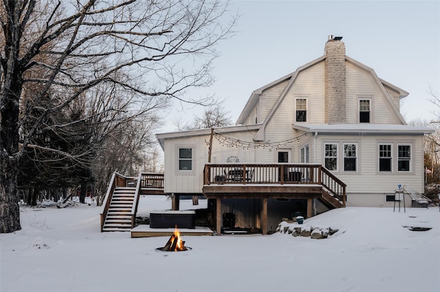 snow covered property featuring a deck, a jacuzzi, and a fire pit