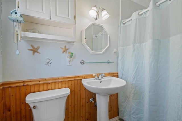 bathroom featuring wood walls and toilet