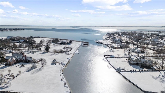 snowy aerial view featuring a water view and a view of the beach