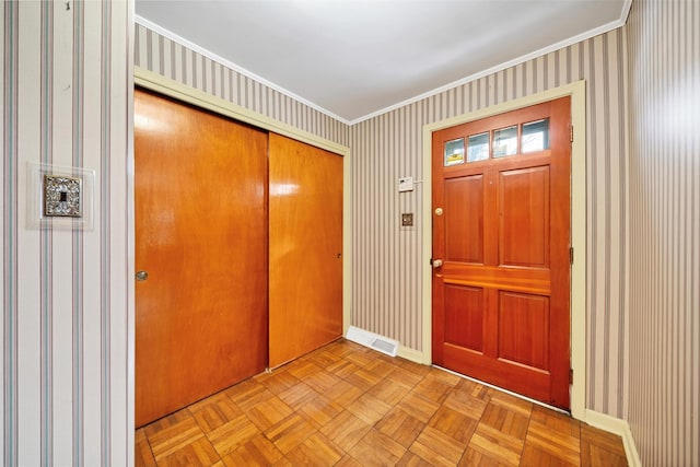 entryway with light parquet floors and ornamental molding