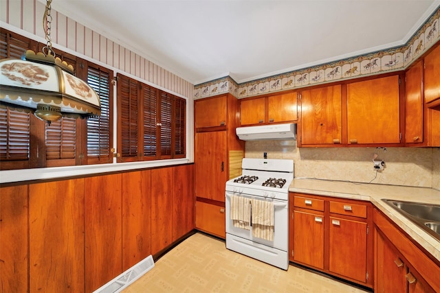 kitchen with white range with gas stovetop, crown molding, and sink