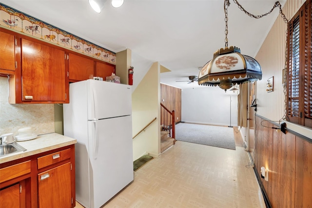 kitchen with decorative light fixtures, ceiling fan, tasteful backsplash, sink, and white refrigerator