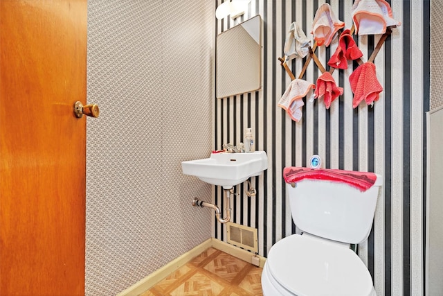 bathroom featuring toilet and parquet flooring