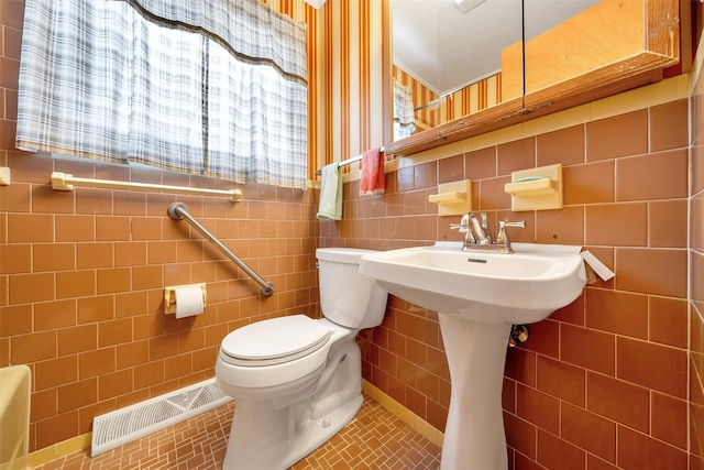 bathroom featuring toilet, tile patterned flooring, and tile walls