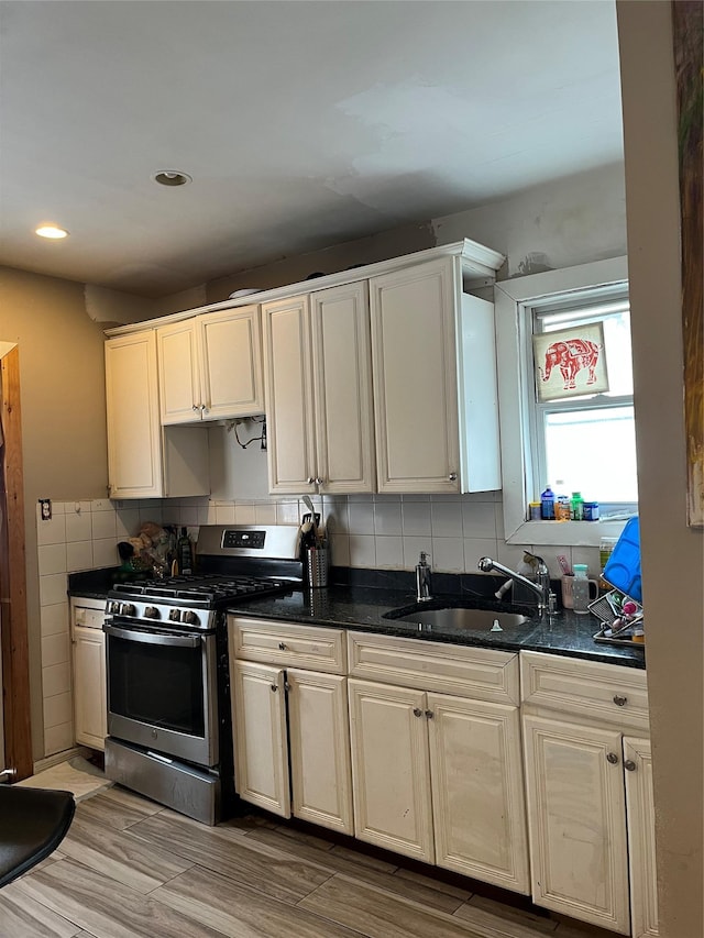 kitchen featuring decorative backsplash, stainless steel range with gas stovetop, and sink