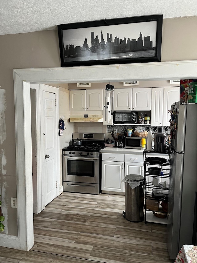 kitchen featuring backsplash, white cabinets, a textured ceiling, and appliances with stainless steel finishes