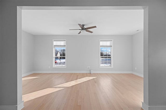 empty room featuring ceiling fan, a healthy amount of sunlight, and light hardwood / wood-style flooring