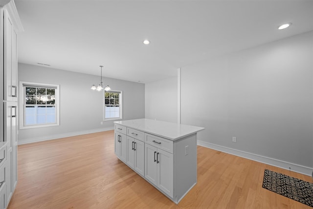 kitchen with a chandelier, a center island, hanging light fixtures, and white cabinets