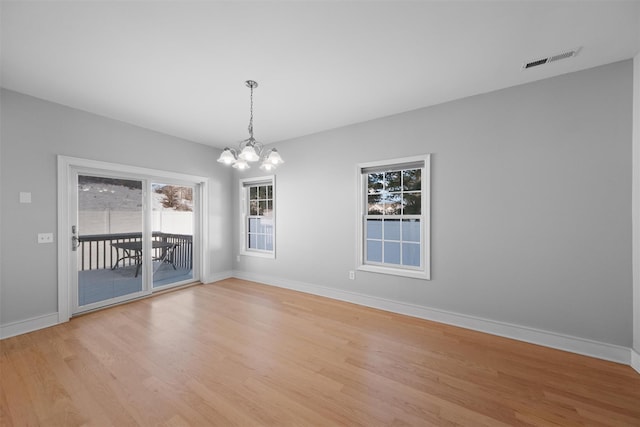 empty room with an inviting chandelier and light hardwood / wood-style flooring