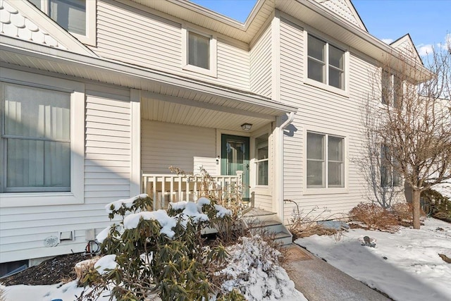 snow covered property entrance featuring a porch