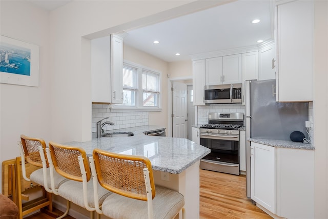 kitchen featuring a breakfast bar area, white cabinets, kitchen peninsula, and stainless steel appliances