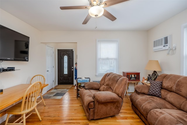 living room with ceiling fan, a wall mounted AC, and light hardwood / wood-style flooring