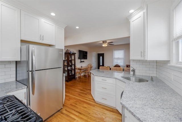 kitchen featuring ceiling fan, decorative backsplash, sink, white cabinets, and stainless steel fridge