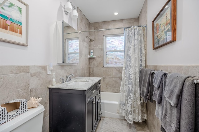 full bathroom with toilet, tile walls, vanity, and shower / bath combo with shower curtain