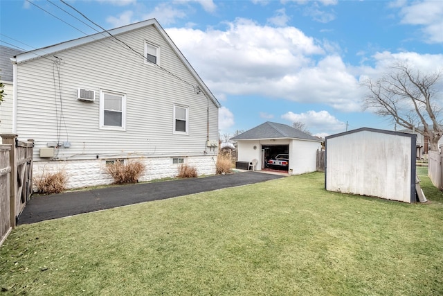 rear view of property featuring a garage, a wall mounted air conditioner, a lawn, and a shed