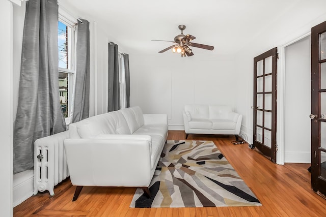 living room featuring ceiling fan, hardwood / wood-style floors, and radiator heating unit