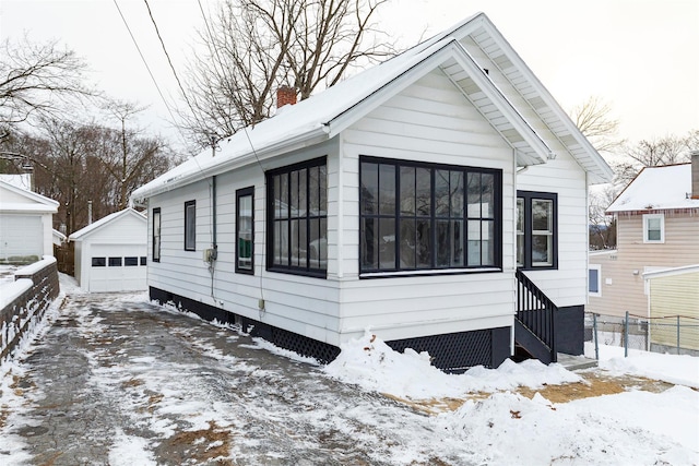 snow covered property featuring an outbuilding and a garage