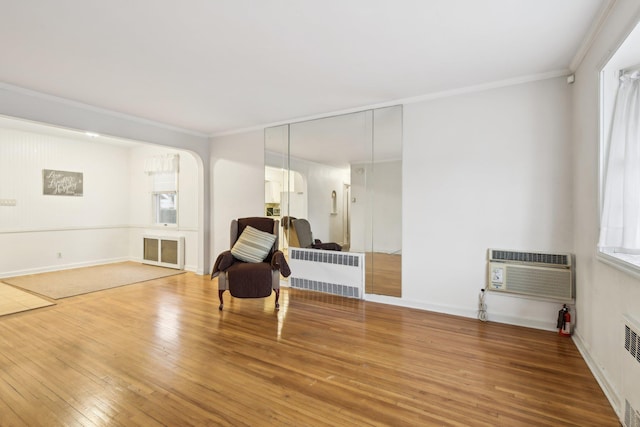 sitting room featuring crown molding, radiator heating unit, hardwood / wood-style floors, and a wall mounted AC