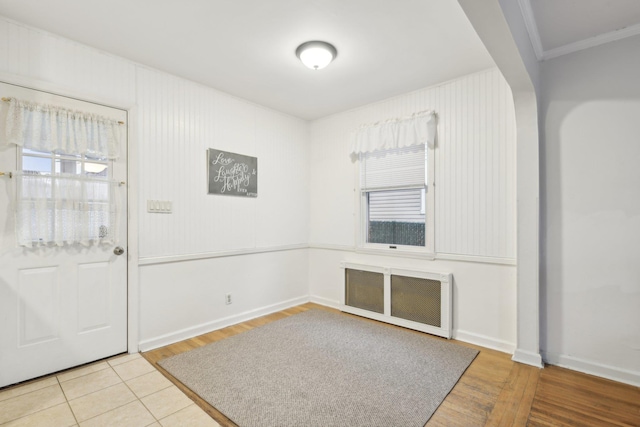 tiled foyer featuring radiator heating unit and ornamental molding