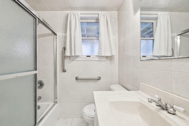 full bathroom featuring tile patterned floors, tile walls, combined bath / shower with glass door, toilet, and vanity