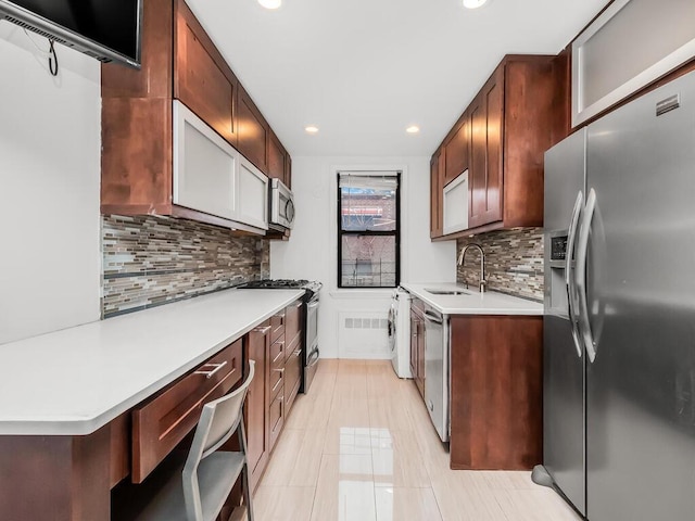 kitchen with light tile patterned floors, stainless steel appliances, backsplash, washer / clothes dryer, and sink