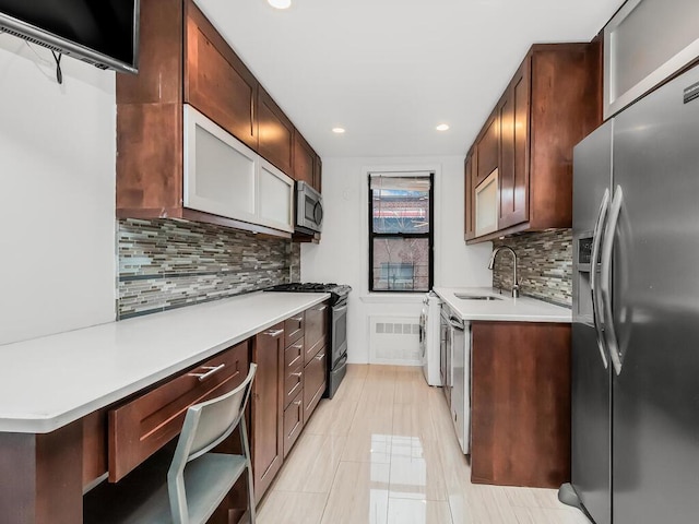 kitchen with appliances with stainless steel finishes, backsplash, washer / clothes dryer, and sink