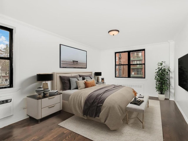 bedroom with radiator heating unit, a wall mounted AC, dark hardwood / wood-style flooring, and crown molding