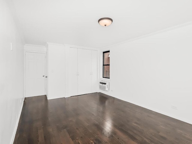 spare room featuring dark wood-type flooring, crown molding, and a wall mounted air conditioner