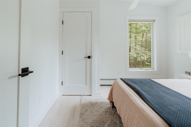 bedroom with a baseboard heating unit, ceiling fan, and light wood-type flooring