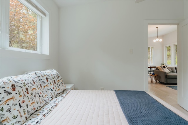 bedroom with light wood-type flooring and an inviting chandelier