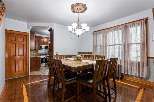 dining space featuring radiator heating unit, dark hardwood / wood-style floors, and a chandelier