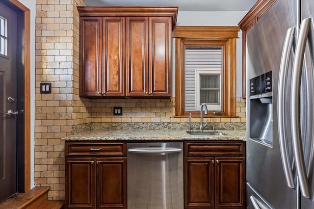 kitchen featuring light stone counters, appliances with stainless steel finishes, sink, and tasteful backsplash