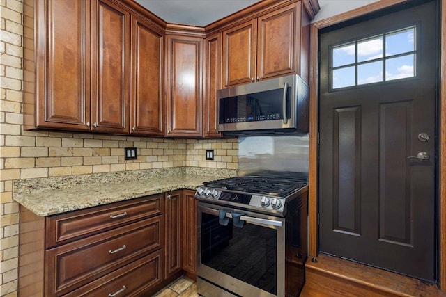 kitchen with light stone countertops, appliances with stainless steel finishes, light tile patterned floors, and decorative backsplash