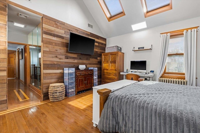 bedroom with wood walls, a skylight, high vaulted ceiling, radiator, and hardwood / wood-style flooring