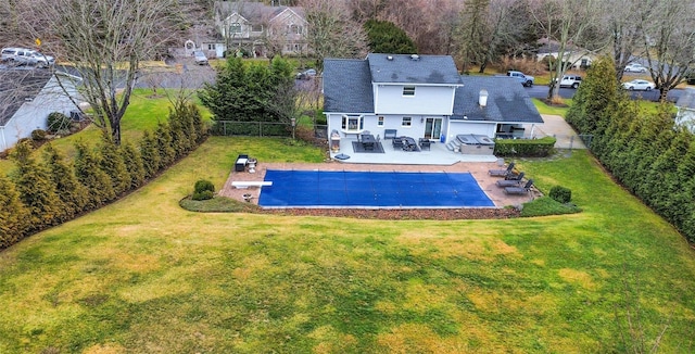 rear view of property with a swimming pool with hot tub, a patio area, and a lawn