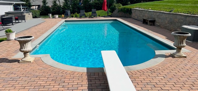 view of pool with a jacuzzi, a patio, and a diving board