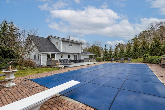 view of pool featuring a diving board, an outdoor kitchen, and a patio area