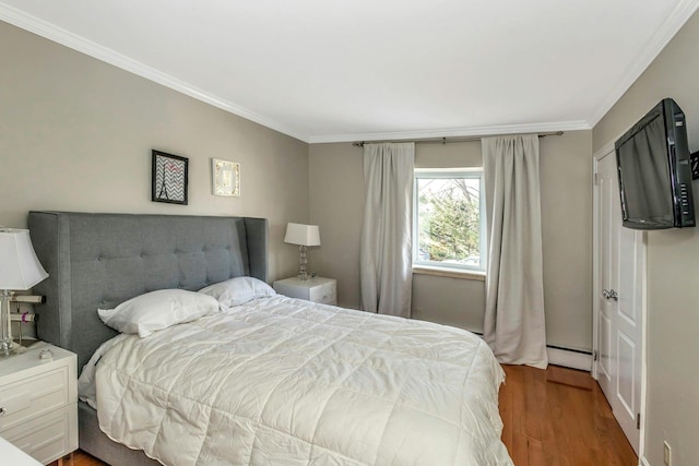 bedroom with a baseboard heating unit, dark wood-type flooring, and crown molding